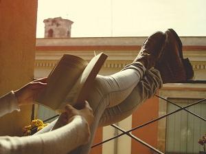 Frau auf Balkon mit Buch